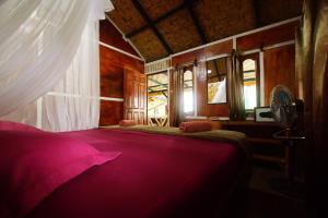 a bedroom with a bed with a pink blanket at Indra Valley Inn Bukit Lawang in Bukit Lawang