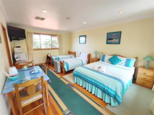 a bedroom with two beds and a desk at Angela's Beach Stays in Apollo Bay