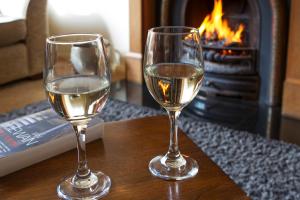 due bicchieri di vino bianco seduti su un tavolo con camino di No4 Low House Cottages a Coniston