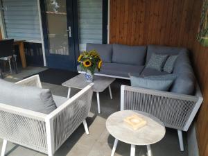 um pátio com um sofá, cadeiras e uma mesa em Chalet "Het Biggetje" met hottub em Volkel
