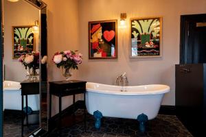 a bathroom with a tub and a mirror and flowers at The Park Hotel in Teddington +37 photos