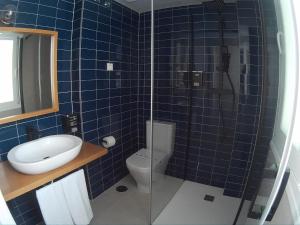 y baño de azulejos azules con aseo y ducha. en Sosiego Hostal de Mar, en Puerto de Mazarrón
