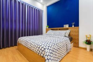 1 dormitorio con cama y pared azul en Kirakuan Luxury 2BR Pool/Gym, en Ho Chi Minh