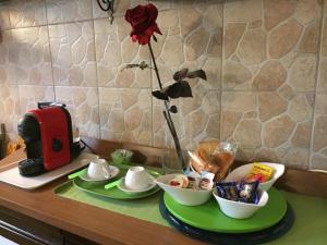 einen Tisch mit einer Rose in einer Vase und etwas Essen in der Unterkunft Il Giardino della Foglia in Bari Palese