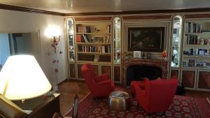 a living room with red chairs and a fireplace at Hotel Locanda San Giacomo in Agliano Terme