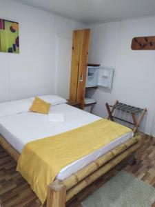 a bedroom with a large bed with a yellow blanket at Posada San Nicolas in San Andrés