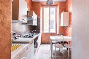 una cucina con elettrodomestici bianchi e tavolo con sedie di Riari 59 Rome - Trastevere a Roma