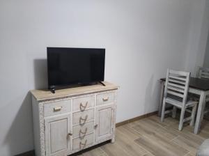 uma televisão em cima de uma cómoda com uma cadeira em Apartamentos Buena Vista 4 em Coto Ríos