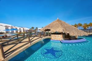 a swimming pool with a straw umbrella and a resort at Costa Caribe Hotel Beach & Resort in La Galera