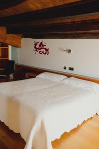 uma cama branca com um adesivo de dragão na parede em Posada Miranda em Miranda del Castañar