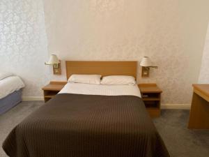 a bedroom with a large bed and two lamps at Waterford Lodge Hotel in Morpeth