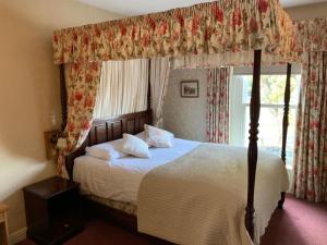 een slaapkamer met een hemelbed en een raam bij Waterford Lodge Hotel in Morpeth