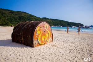 a barrel sitting on a beach with people playing at Paradise Hostel Ilha Grande in Abraão