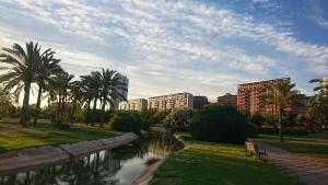 a river in a city with palm trees and buildings at Beach Luxury Apartment in Valencia