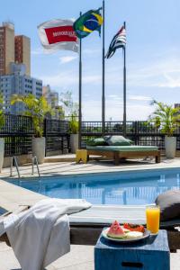 a swimming pool with a plate of food on a table at Monreale Plus Midtown Campinas in Campinas