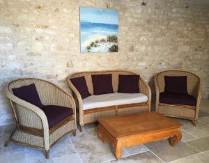 ドリュ・ドレロンにあるL'écurie & Le Chai - Gîtes de charme entre plage et cœur de villageの籐の椅子2脚、コーヒーテーブルが備わります。