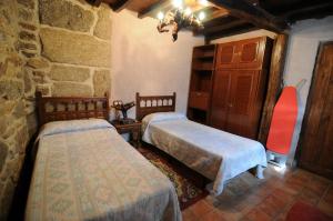 a bedroom with two beds and a stone wall at La Resbalina Casa Rural in Cabeza del Caballo