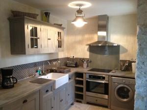 a kitchen with a sink and a stove at L'écurie & Le Chai - Gîtes de charme entre plage et cœur de village in Dolus d'Oléron