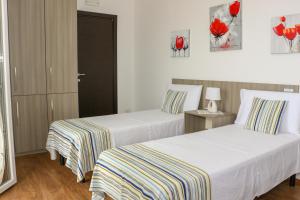 two beds in a hotel room with red flowers on the wall at B&B Incanto Salento in Ugento