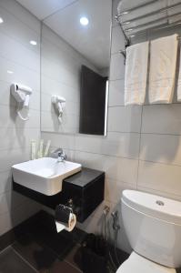 a white bathroom with a sink and a toilet at Dreamtel Kota Kinabalu in Kota Kinabalu