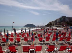a group of chairs and umbrellas on a beach at House Mare e Monti by Holiday World in Albenga