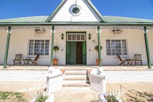 a front porch of a white house with a green door at Victorian Square Guesthouse in Graaff-Reinet