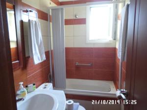 een badkamer met een bad, een wastafel en een douche bij Stella Apartments in Petra