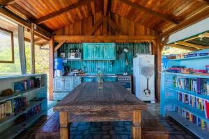 a large wooden table in a kitchen with books at Sunset Strip Eco Apartments in Florianópolis