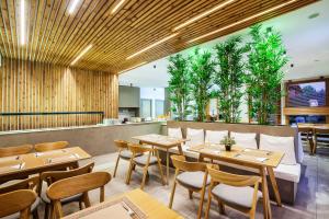 a restaurant with wooden tables and chairs and plants at Palladium Hotel in Kriopigi
