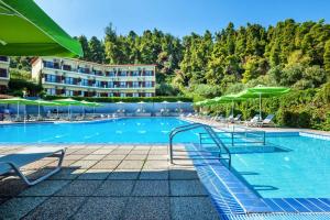 a large swimming pool with chairs and umbrellas at Palladium Hotel in Kriopigi
