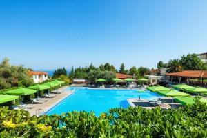 a large swimming pool with green umbrellas and chairs at Palladium Hotel in Kriopigi