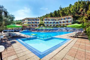a large swimming pool with a hotel in the background at Palladium Hotel in Kriopigi
