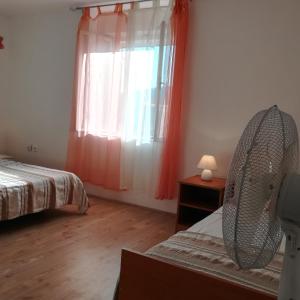 - une chambre avec 2 lits et une fenêtre avec des rideaux orange dans l'établissement Kuća za odmor Marina, à Sutomišćica