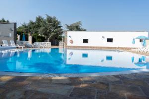 a swimming pool with chairs and a building at Corallo Country House in Noci