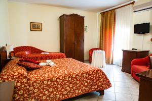 Cette chambre d'hôtel comprend deux lits et un fauteuil rouge. dans l'établissement Hotel Il Cavalier D'Arpino, à Arpino