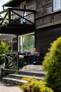 a man and a dog sitting at a table outside of a house at Dandzenieki in Pāvilosta