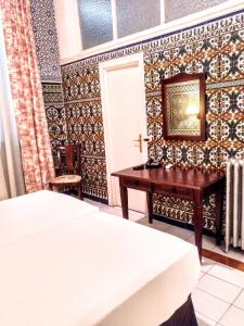 a bedroom with a bed and a table and a mirror at Hotel Simon in Seville