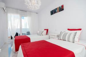 a white bedroom with two beds with red sheets at Casa Chana in Almuñécar