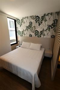 1 dormitorio con cama blanca y papel pintado con motivos florales en YOU Plus by INN, en Santa Cruz de la Sierra