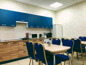 uma cozinha com cadeiras azuis, uma mesa e armários azuis em Annet em Kharkov