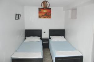 two twin beds in a room with white walls at Sunny Apartments Taghazout in Taghazout