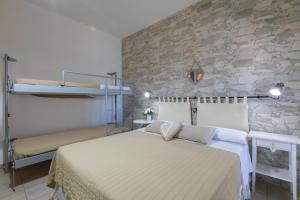 une chambre avec un lit et un mur en pierre dans l'établissement B&B L'isola che non c'è, à Torre San Giovanni