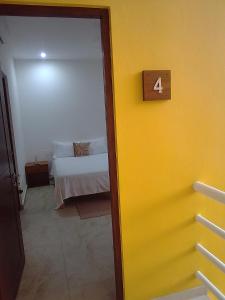 Habitación con cama y pared amarilla en posada tumben ka´a en Tulum