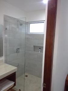 a bathroom with a shower with a glass door at posada tumben ka´a in Tulum