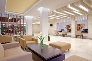 a lobby with couches and a table and chairs at Hotel Surya Yudha Purwokerto in Purwokerto