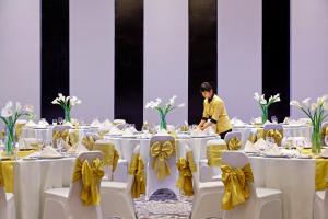 un hombre de pie en una habitación llena de mesas con arcos amarillos en Hotel Surya Yudha Purwokerto, en Purwokerto