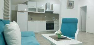 una cocina con 2 sillas azules y una mesa en Apartmani Bilić en Korenica