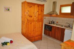 a kitchen with wooden cabinets and a bed in a room at Lysistrata Bungalows in Potos