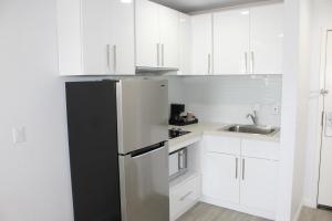 een keuken met witte kasten en een zwarte koelkast bij Mirage Inn & Suites in San Francisco