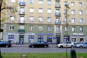 duży budynek z zaparkowanymi przed nim samochodami w obiekcie Apartament Nowowiejskiego w mieście Częstochowa